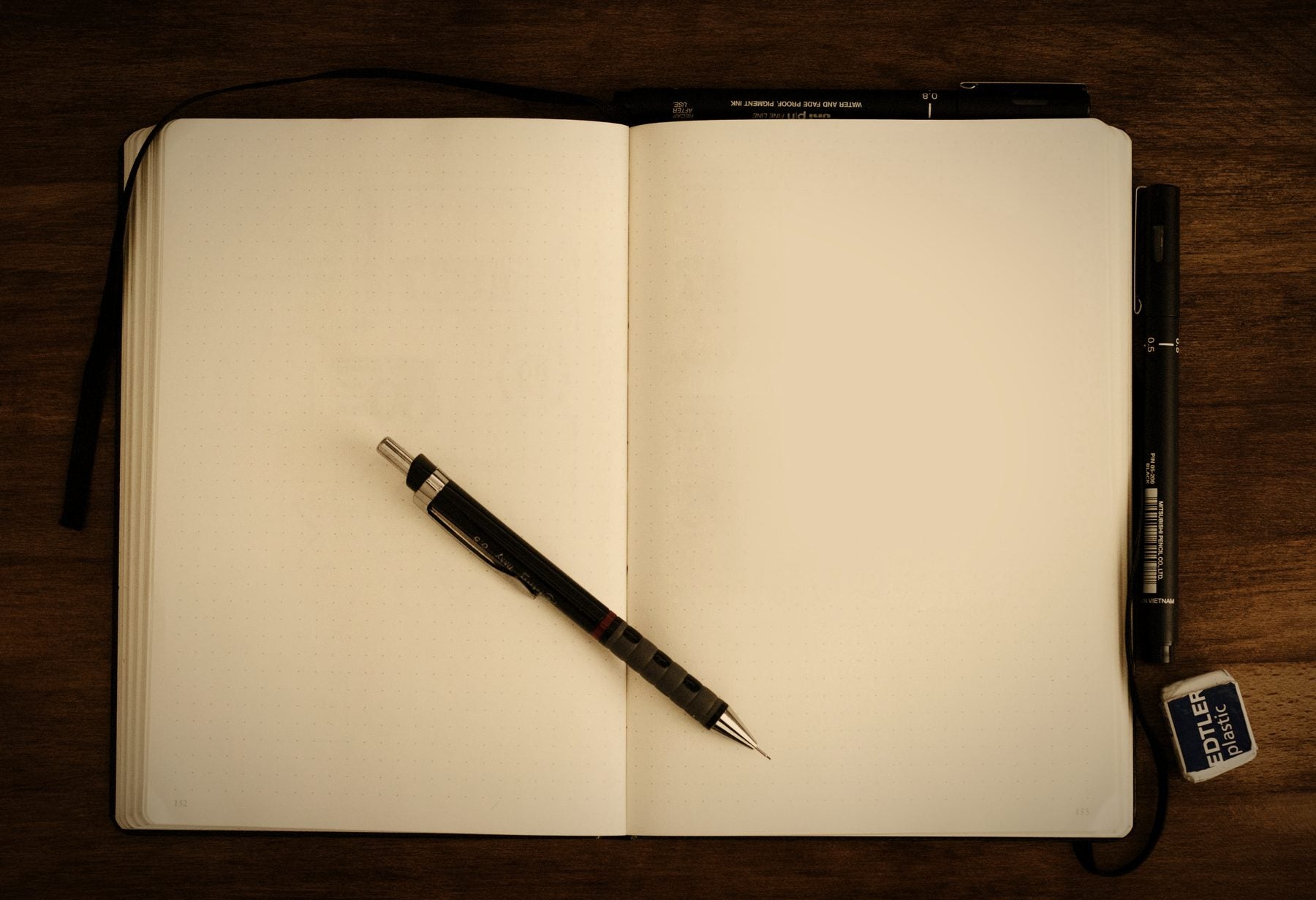 Cuaderno abierto con un portaminas sobre una mesa de madera